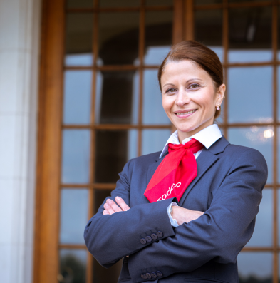 A woman in a suit and red tie posing outside