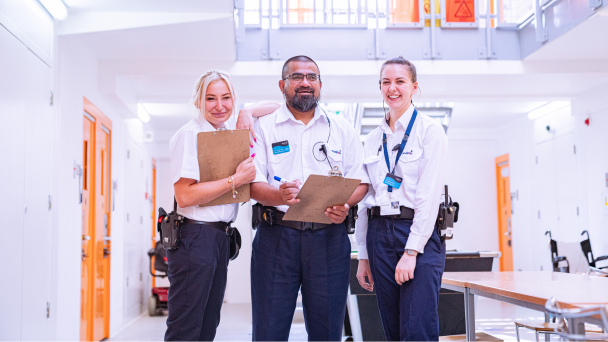 Three people in uniform standing in a hallway, ready for duty. 