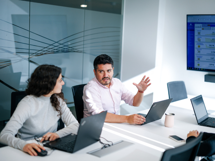 A diverse group of professionals in a meeting room, taking and discussing with each other 