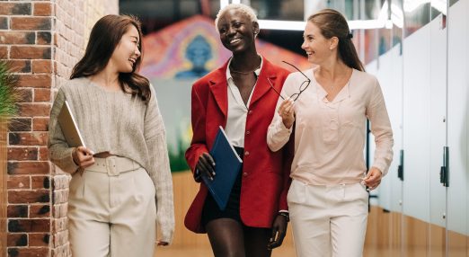 Three girls walk along a corridor smiling