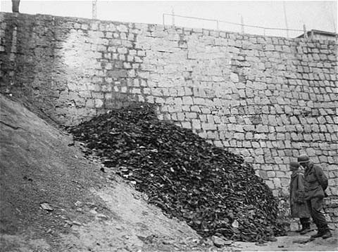 After the liberation of the Flossenbürg concentration camp, two US army infantrymen examine a pile of shoes belonging to victims ...