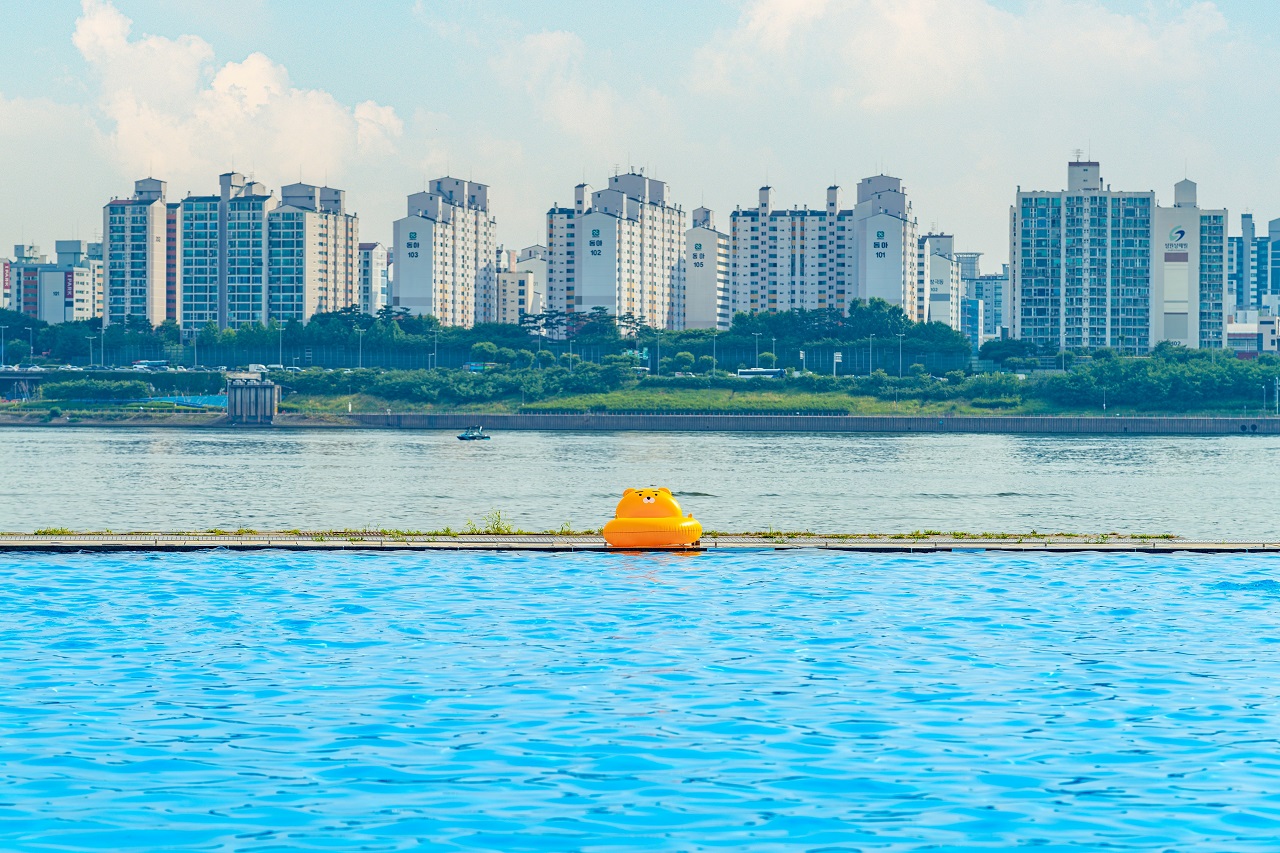 A picture of Nanji Hangang Park's water playground with a yellow tube floating in the background of an apartment complex