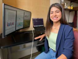 Yakelyn Ramos Jauregui sits at a desk with a computer screen behind