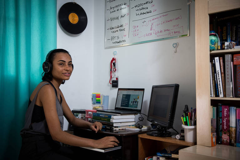 jovem parda, com fone de ouvido, em frente a um notebook