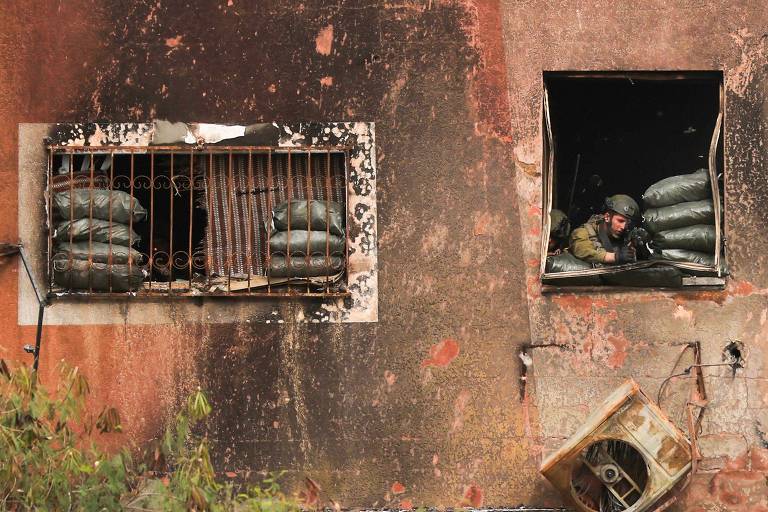 Soldado de Israel se posiciona em janela de prédio destruído na Cidade de Gaza