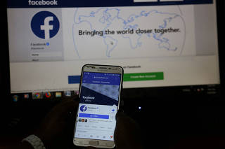 FILE PHOTO: An illustration photo shows the Facebook page displayed on a mobile phone internet browser in front of a computer screen at a cyber-cafe in Nairobi, Kenya