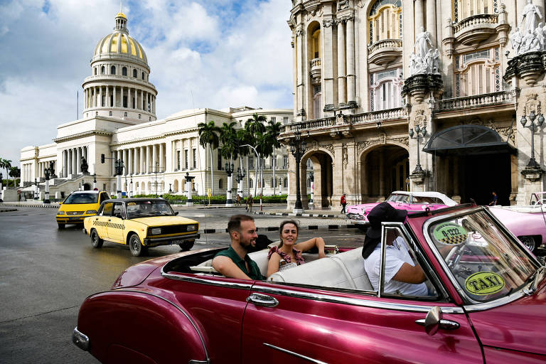 Turistas andam em um carro clássico americano em uma rua de Havana em 21 de outubro de 2024