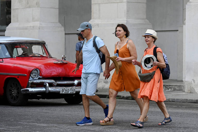 Turistas caminham por uma rua de Havana