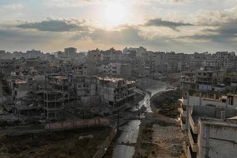 This aerial picture shows people walking past destroyed buildings in the centre of Homs on December 20, 2024. Islamist-led rebels took Damascus in a lightning offensive on December 8, ousting president Bashar al-Assad and ending five decades of Baath rule in Syria. (Photo by Sameer Al-DOUMY / AFP)