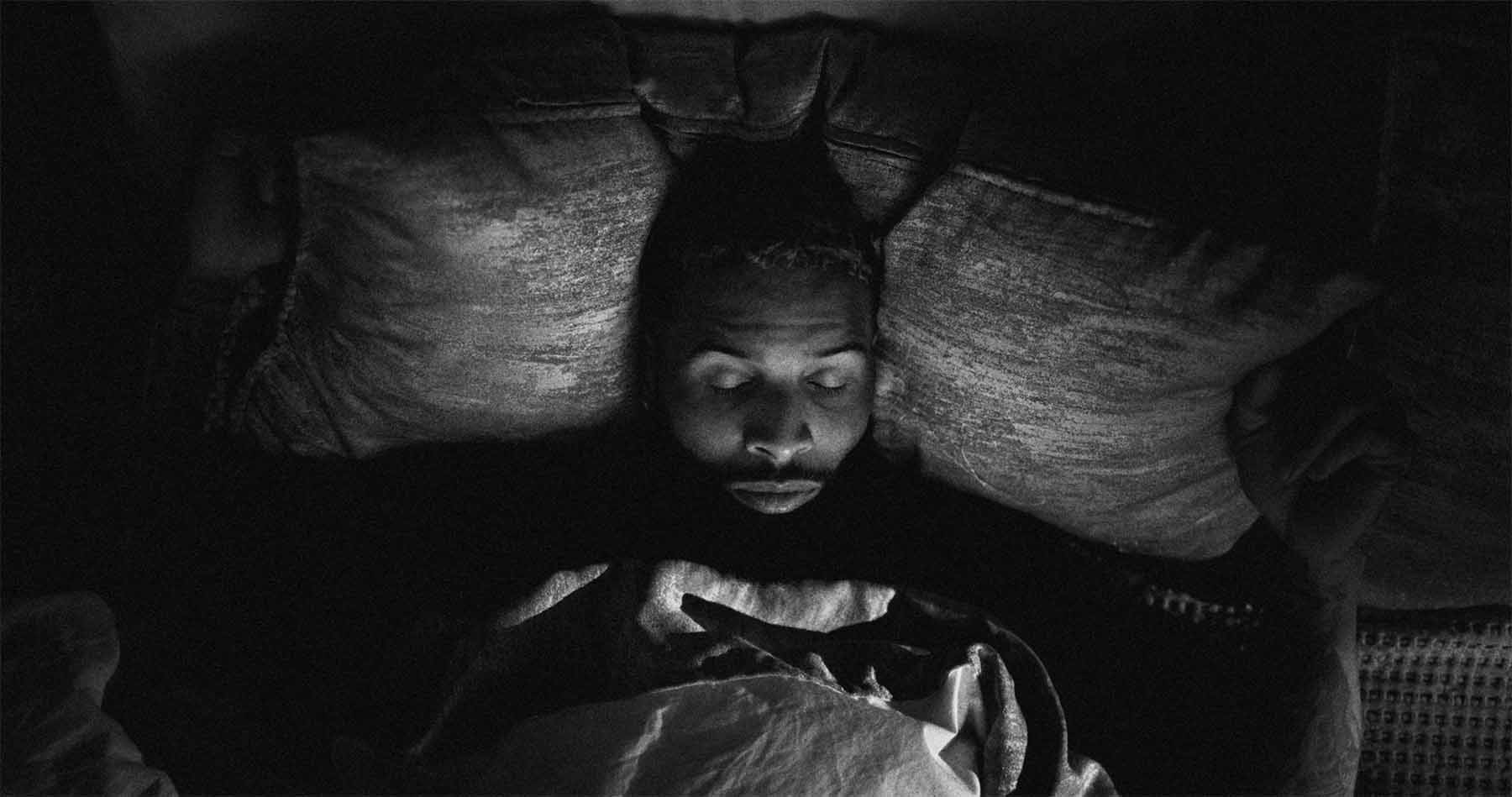 black and white shot of a man lying in bed with his eyes closed