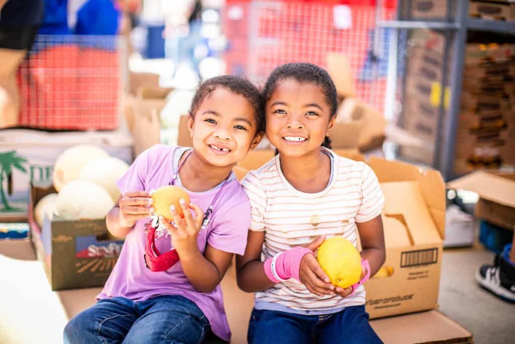 Two sisters posing with fresh produce