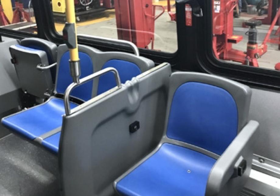 A bench of two seats flipped down next to a single seat flipped up. A barrier separates these seats from a single stationary seat.