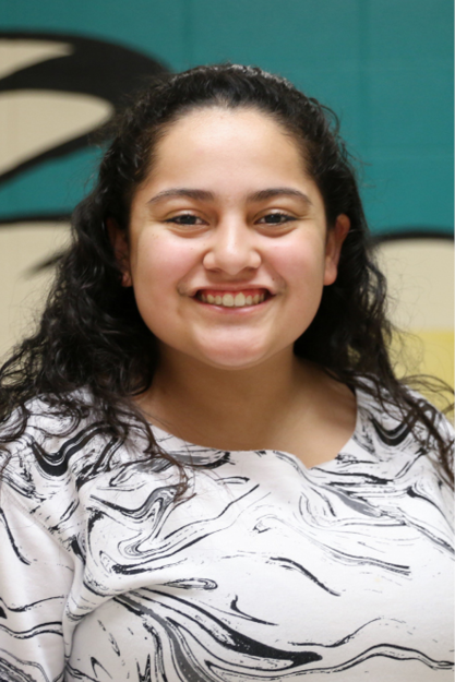 Raquel Banda smiles at the camera, wearing a white shirt with a black and gray marbled pattern.