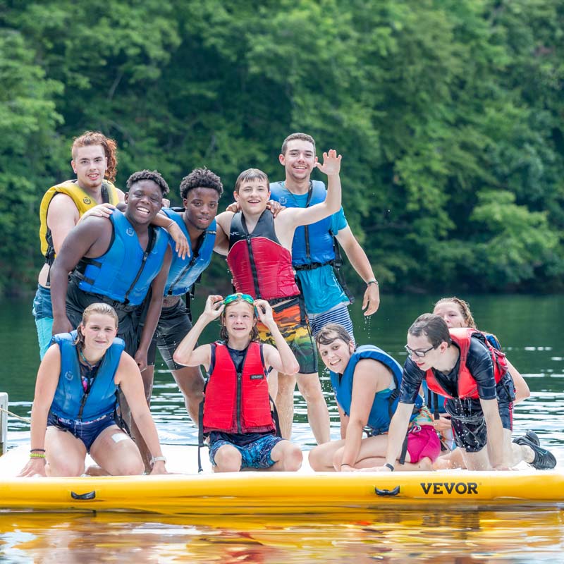 Kids in life jackets swimming at a lake