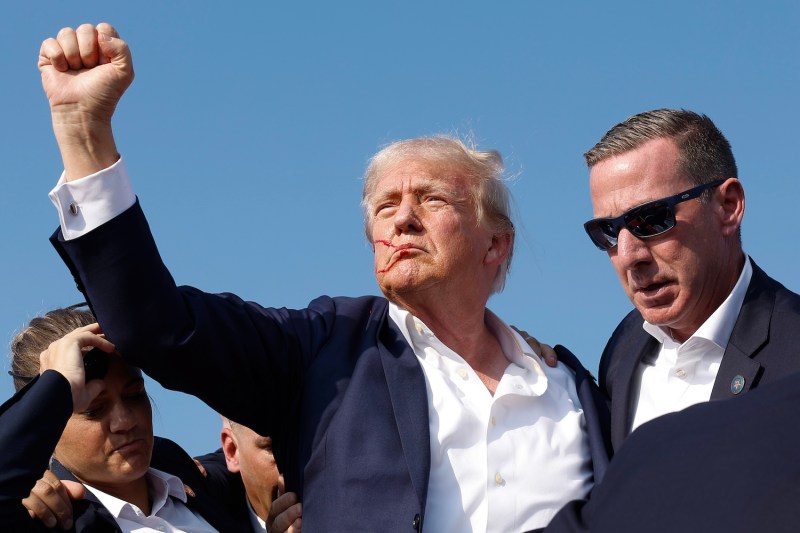 Republican presidential candidate and former U.S. President Donald Trump pumps his fist as he is rushed offstage during a rally in Butler, Pennsylvania, blood on his face.