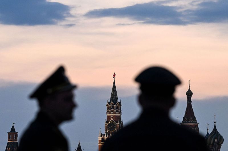 Russian servicemen stand with the Kremlin's Spasskaya tower and Saint Basil's cathedral before the Victory Day military parade rehearsal in central Moscow, on April 27, 2023.