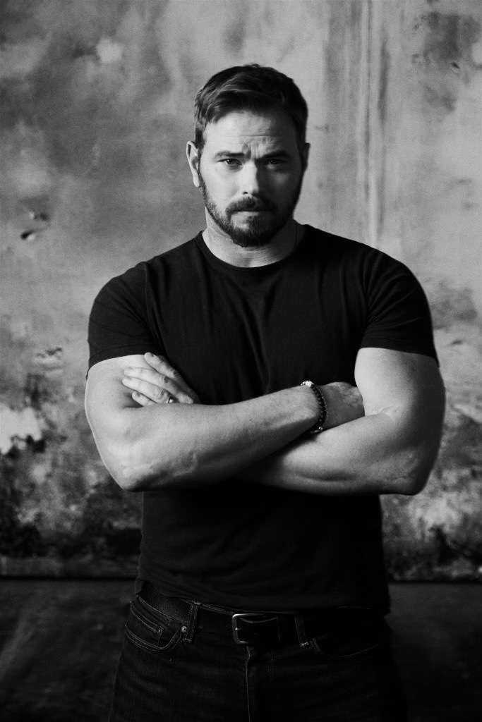 Kellan Lutz with arms folded looking at camera