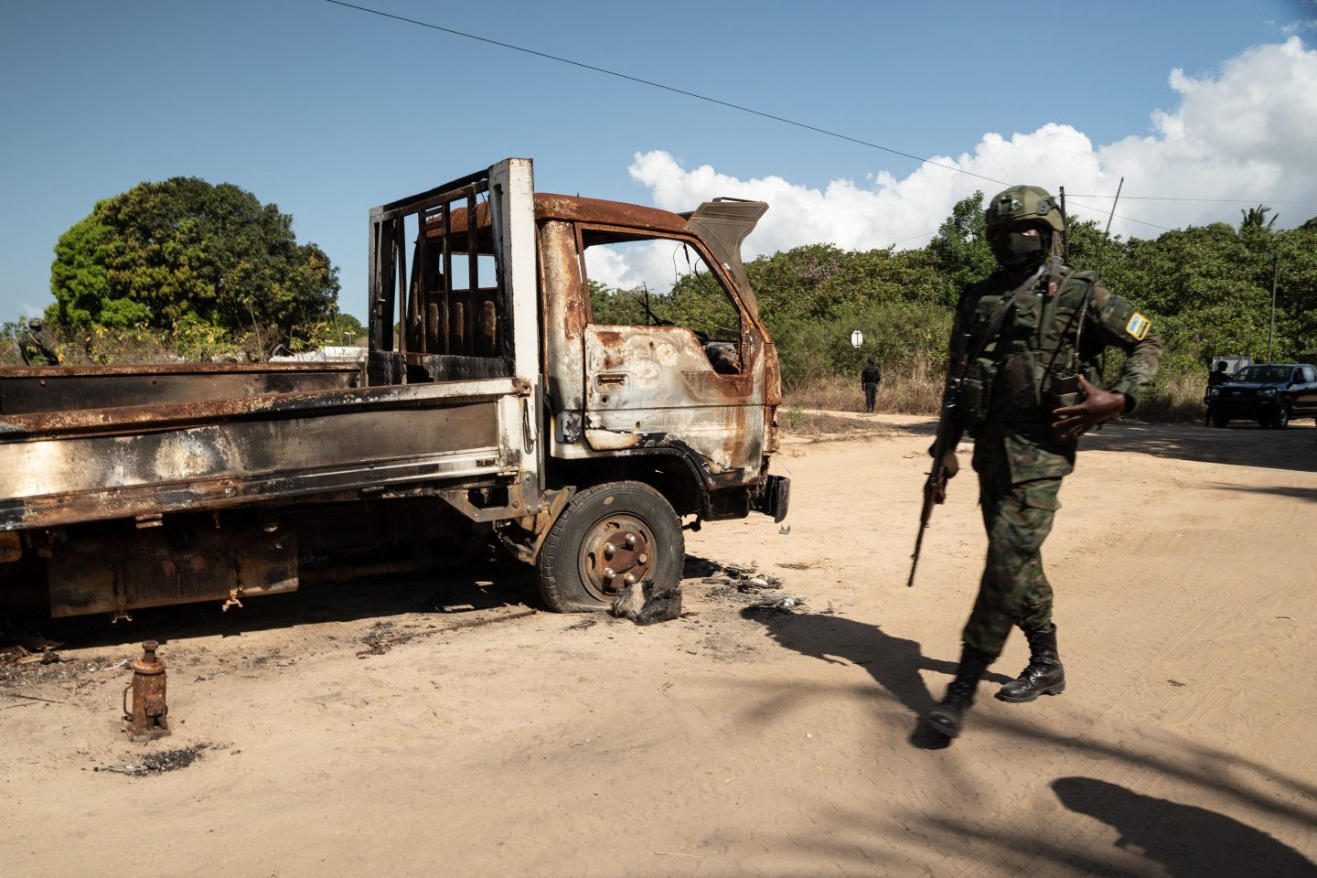 A Rwandan soldier walks in front of a burned truck near Palma