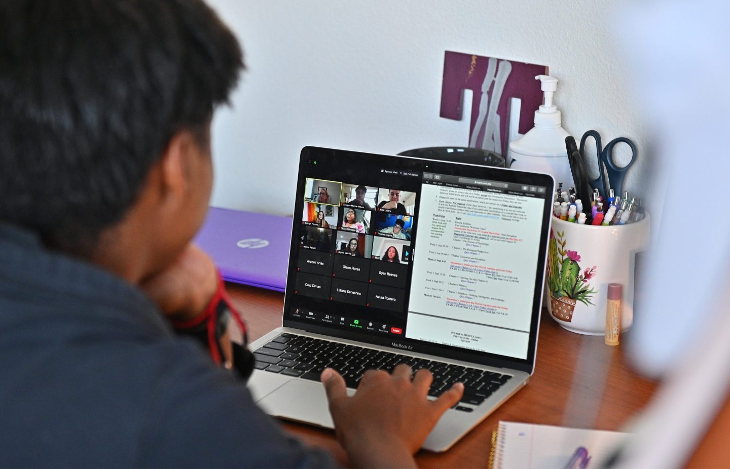 a freshman, sits at a desk in her dorm room as she participates in a Zoom meeting