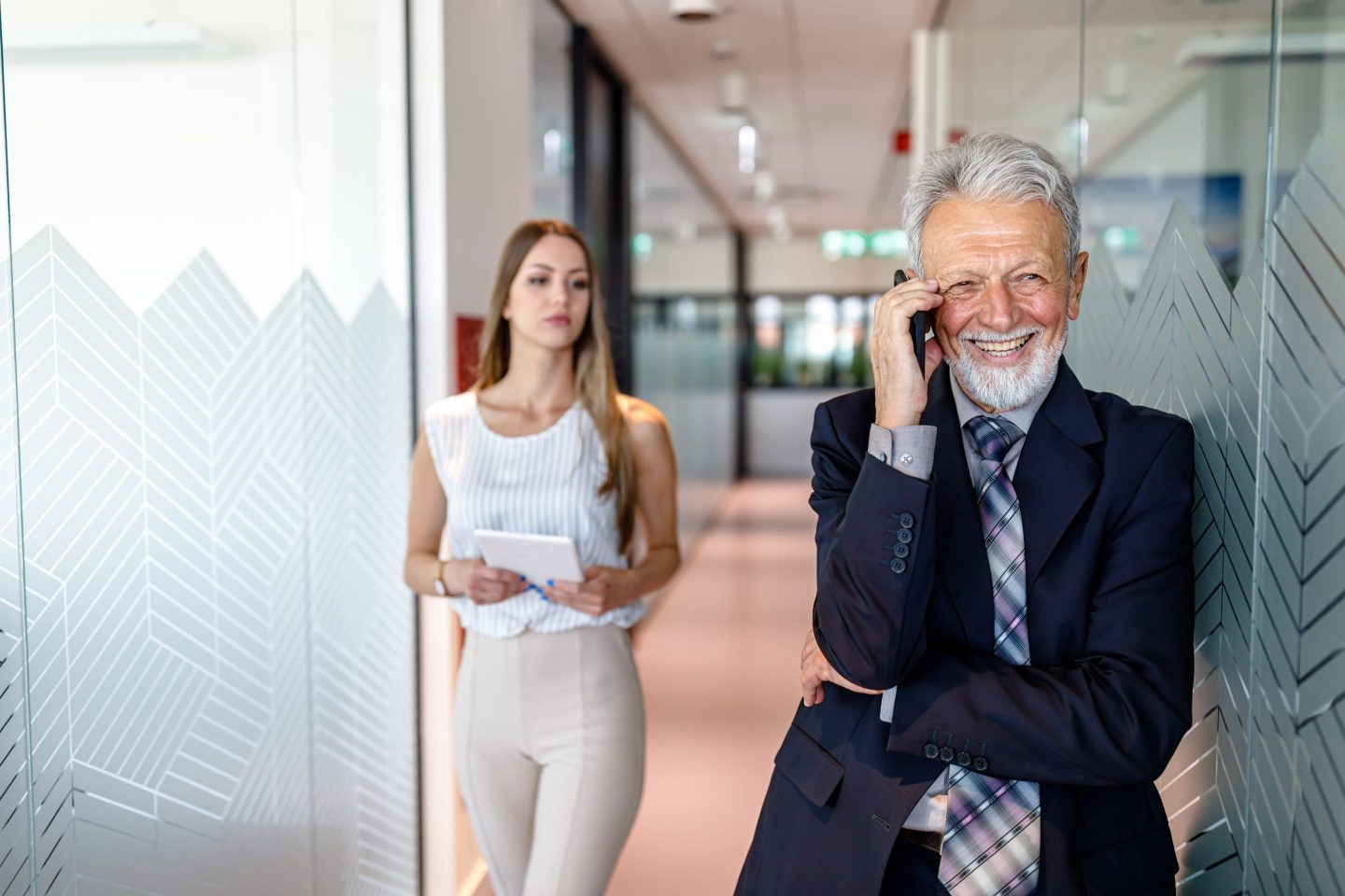 Senior Handsome Business Person is Standing in the Hall and Talking over the Phone.