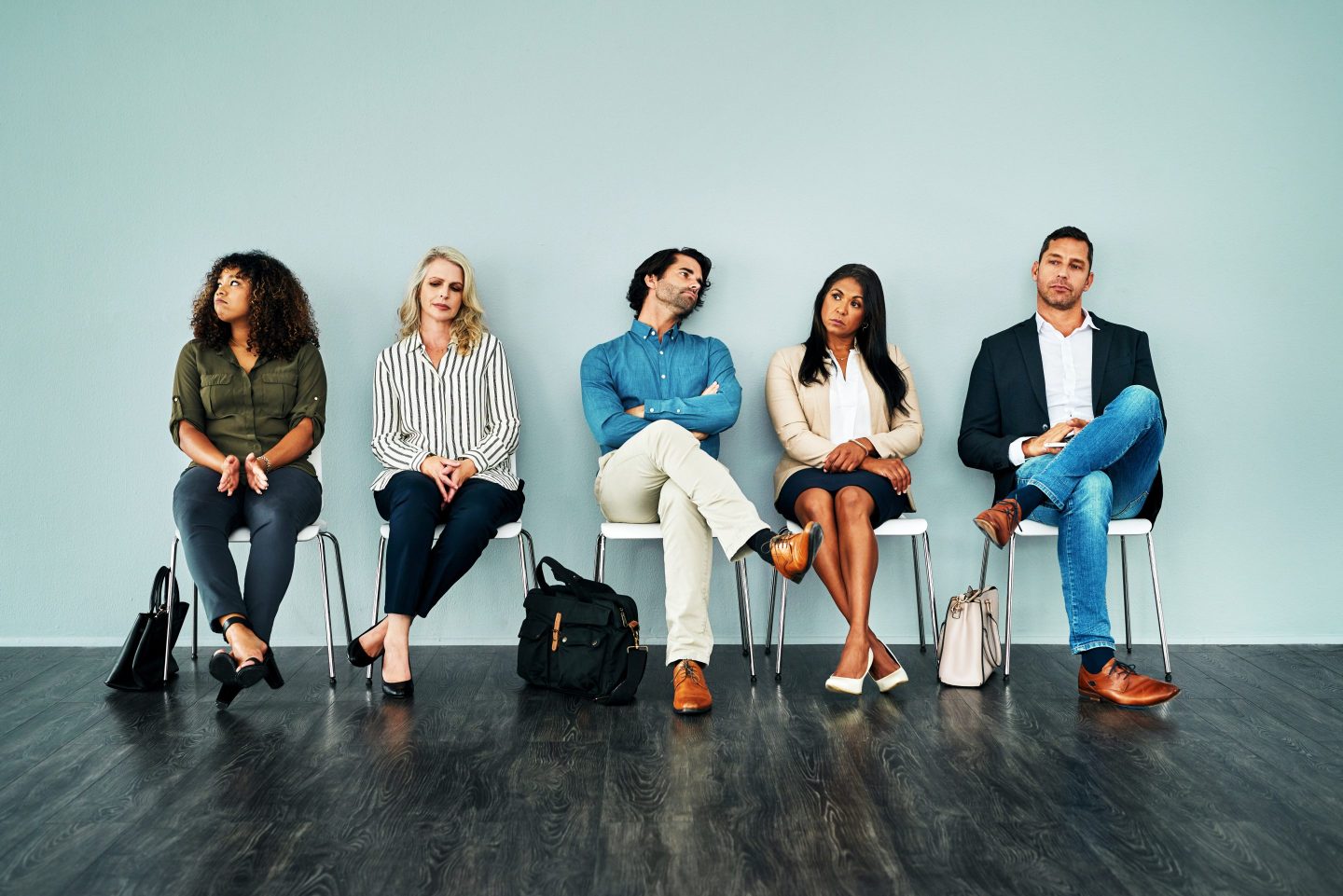 Studio shot of a group of businesspeople looking bored while waiting in line against a blue background