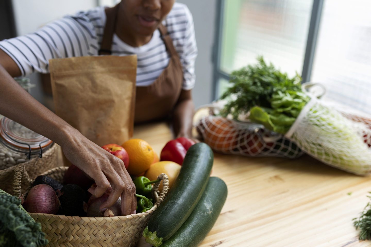 woman unpacking fruit and vegetables onto kitchen counter