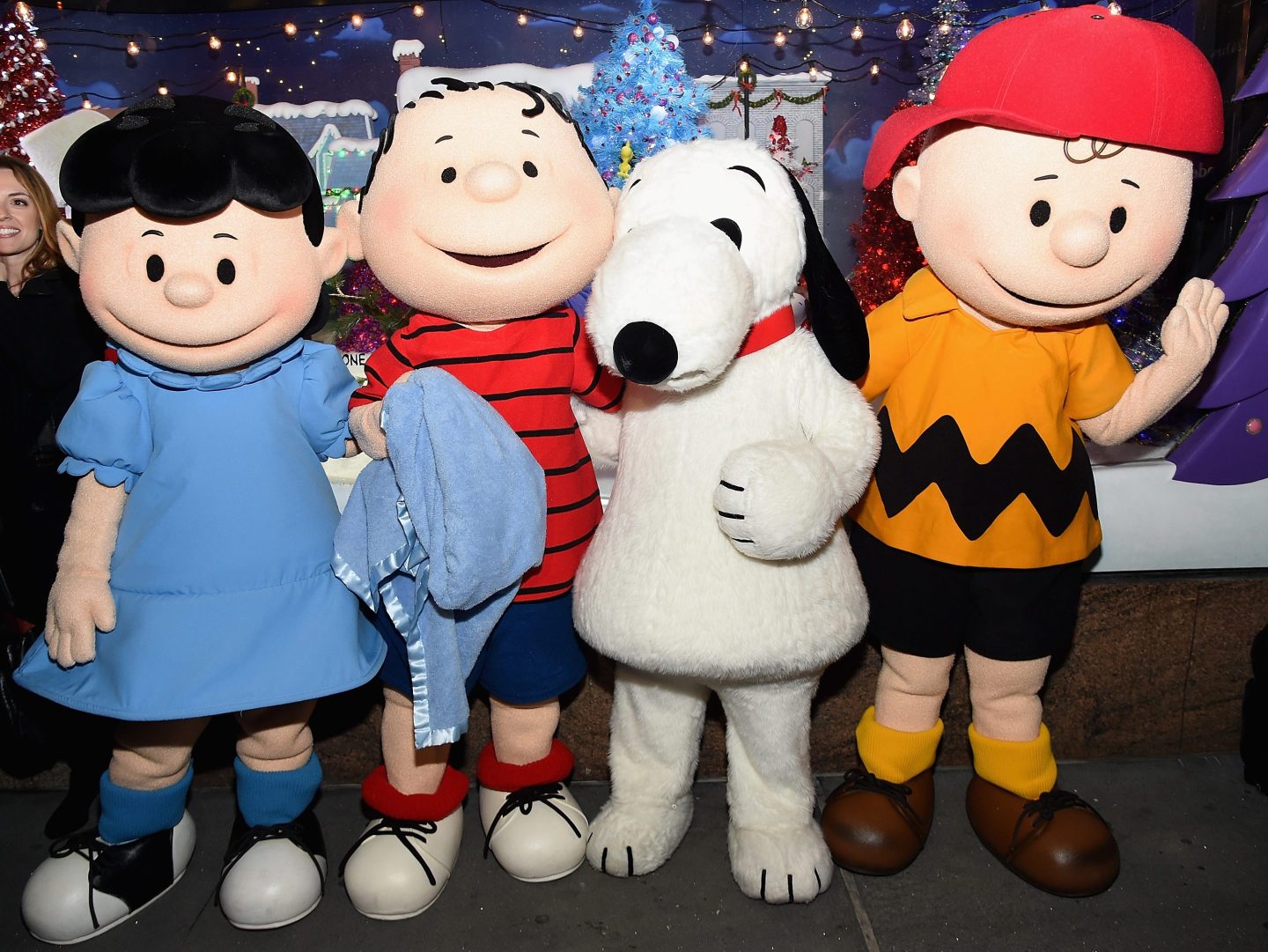 The Peanuts pose in front of a Peanuts inspired Christmas window.