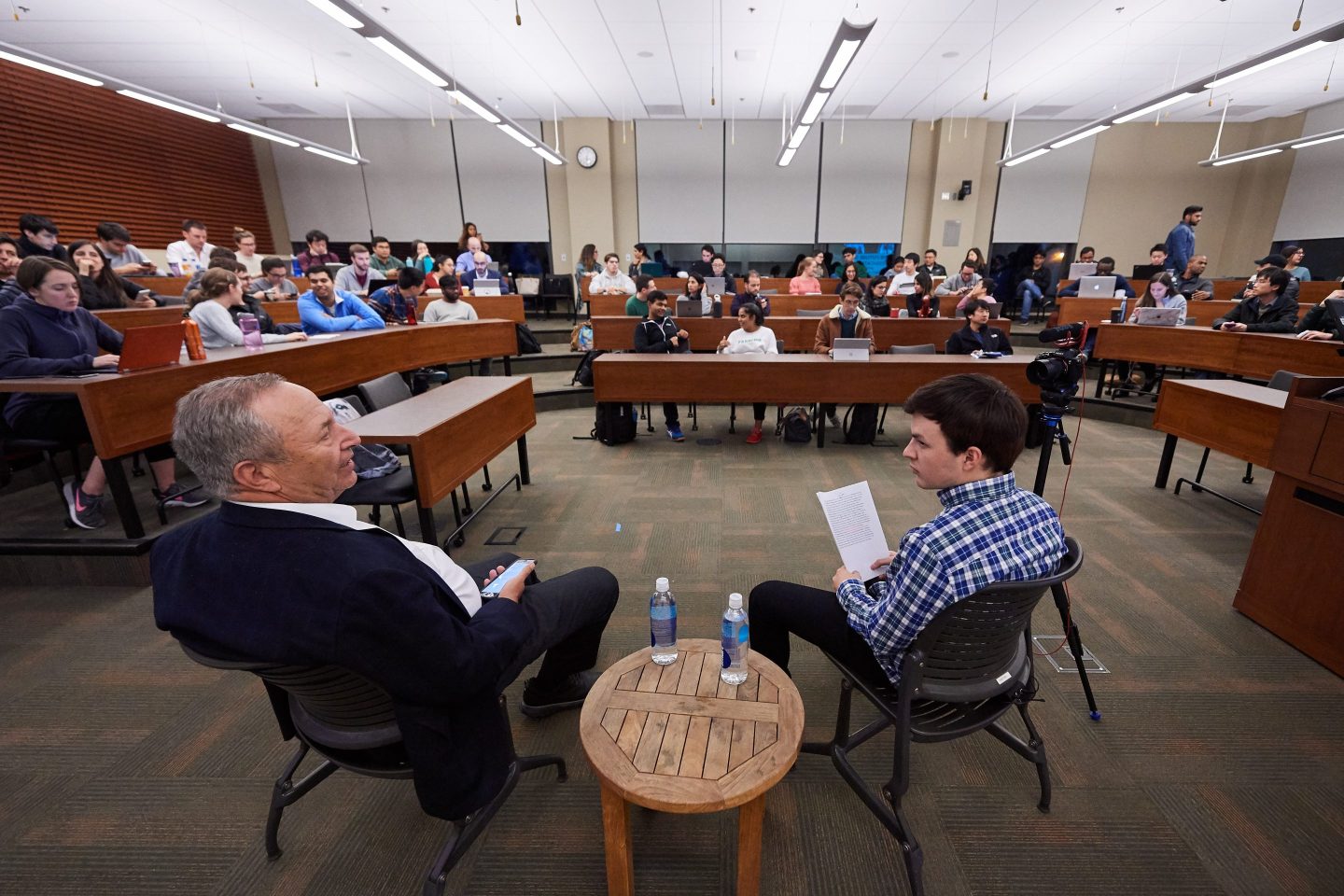 Larry Summers and Jamie Beaton sit in the front of a college classroom.