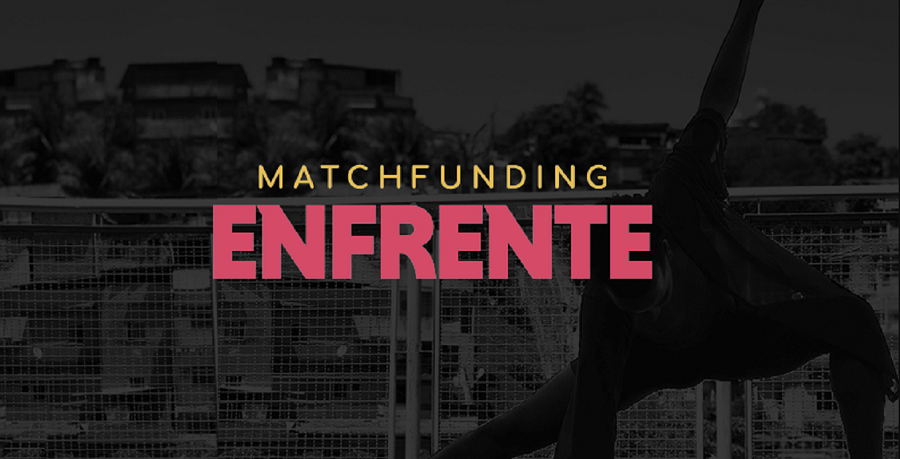 Imagem em preto e branco de uma pessoa dançando em frente à paisagem de uma comunidade. Há sobre essa imagem o logo do Matchfunding Enfrente nas cores rosa e amarela.