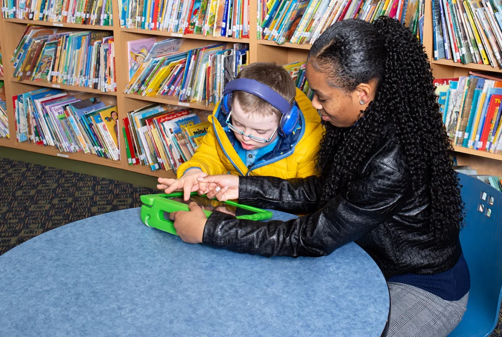 Instructional assistant helps student with learning device