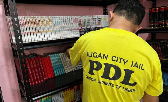 A prisoner arranges books in the library at Iligan City Jail.