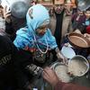 Displaced Palestinians collect food at a distribution point near a school-turned-shelter in Gaza.