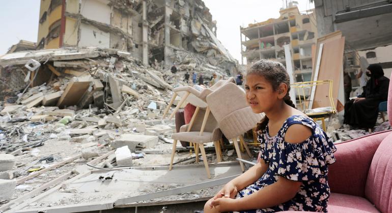 Una niña sentada entre los escombros de edificios destruidos en Gaza.