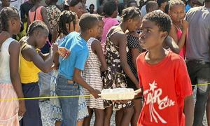 Des enfants haïtiens font la queue pour recevoir un repas chaud et de l'eau distribués par le PAM à Port-au-Prince.