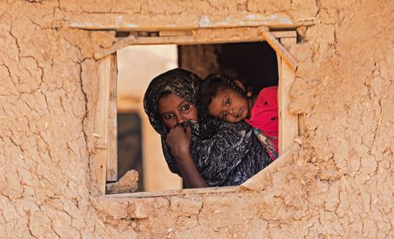 A child and mother peer through a window in Alsabaat community, Kassala state.