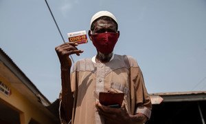 A 76-year-old man shows his vaccination card after receiving a COVID-19 vaccine in Kasoa, Ghana.