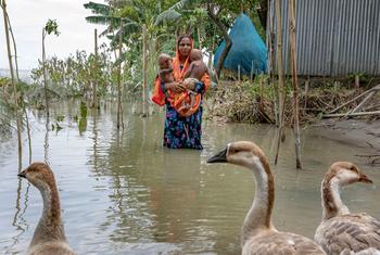 A mother carries her daughters through flood waters during July's monsoon season in Bangladesh.