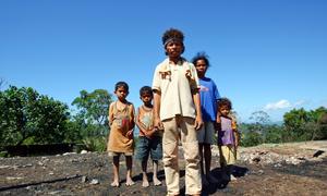 A family stands in front of the ruins of their house which was burned down during a period of civil unrest.