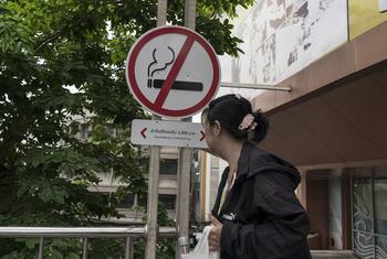 A woman walks past a no smoking sign outside a shopping centre in Bangkok, Thailand.