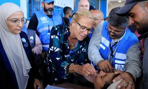 Sigrid Kaag, Senior Coordinator for Humanitarian Affairs and Reconstruction in Gaza, administers a dose of the polio vaccine to a child in Gaza.