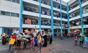 Families sheltering in an UNRWA school collect mattresses.