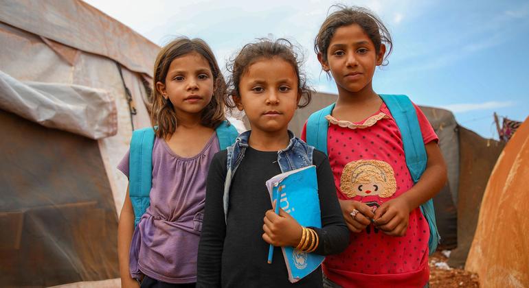 فتيات سوريات يحملن حقائب مدرسية من اليونيسف، يقفن خارج خيمة مدرسية في موقع إيواء في إدلب، شمال سوريا.