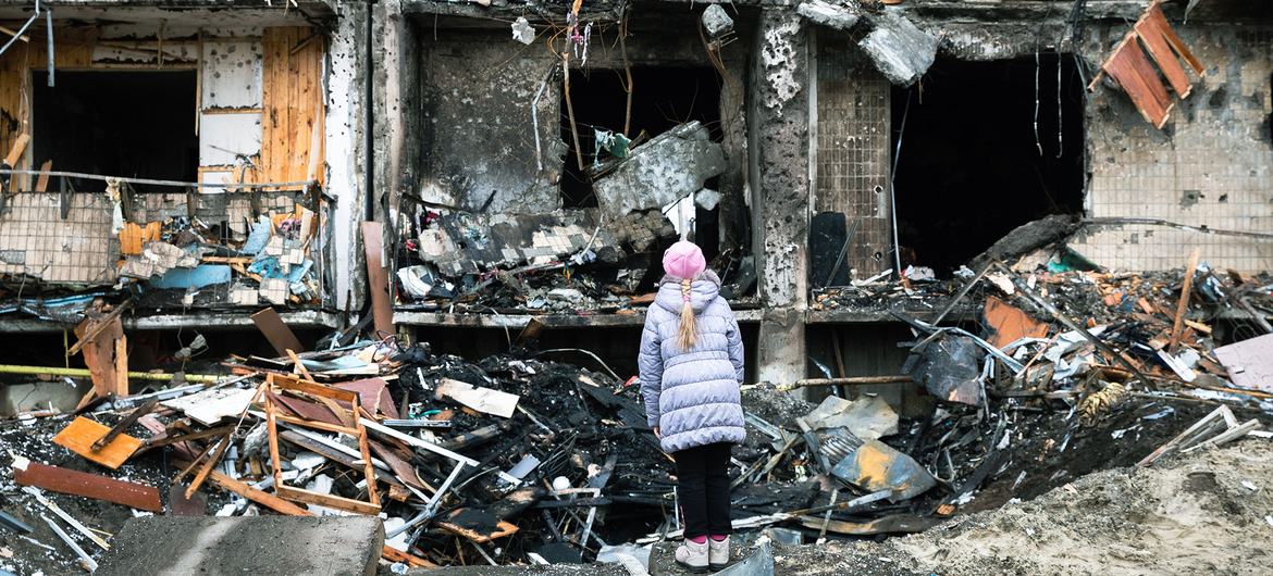 On 25 February 2022 in Kyiv, Ukraine, a girl looks at a crater left by an explosion in front of an apartment building which was heavily damaged during ongoing military operations.