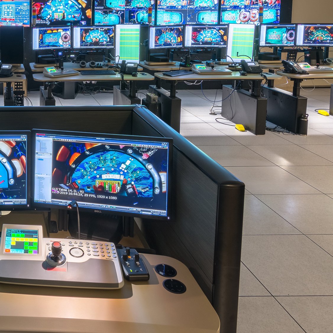 a bunch of computer stations inside a room with a wall of monitors