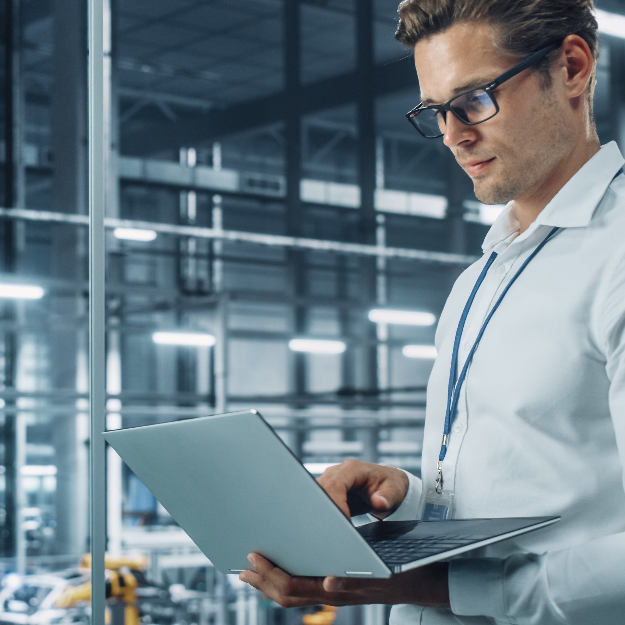 Man standing in a server room holding a laptop