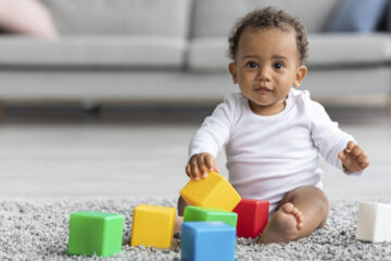 baby with blocks demonstrates updated developmental milestones