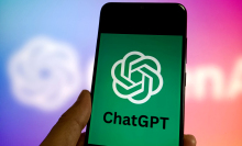 A hand holds a phone with the ChatGPT logo on the screen.