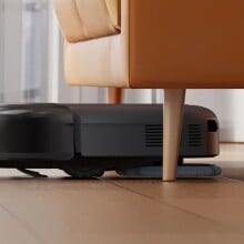 a eufy robot vacuum cleans under the couch with a baseball in front of it