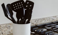 black kitchen utensils in a jar by a stove