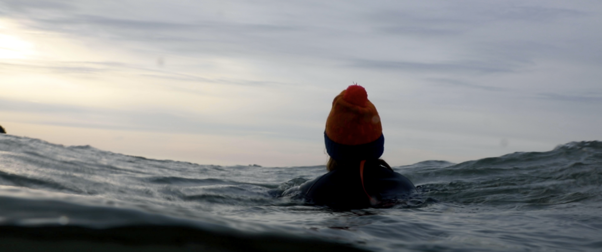 A still from the film of a woman with her back turned to the camera, practicing cold-water swimming.